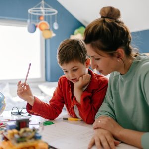 Photo of a young boy being homeschooled by his mother in his bedroom