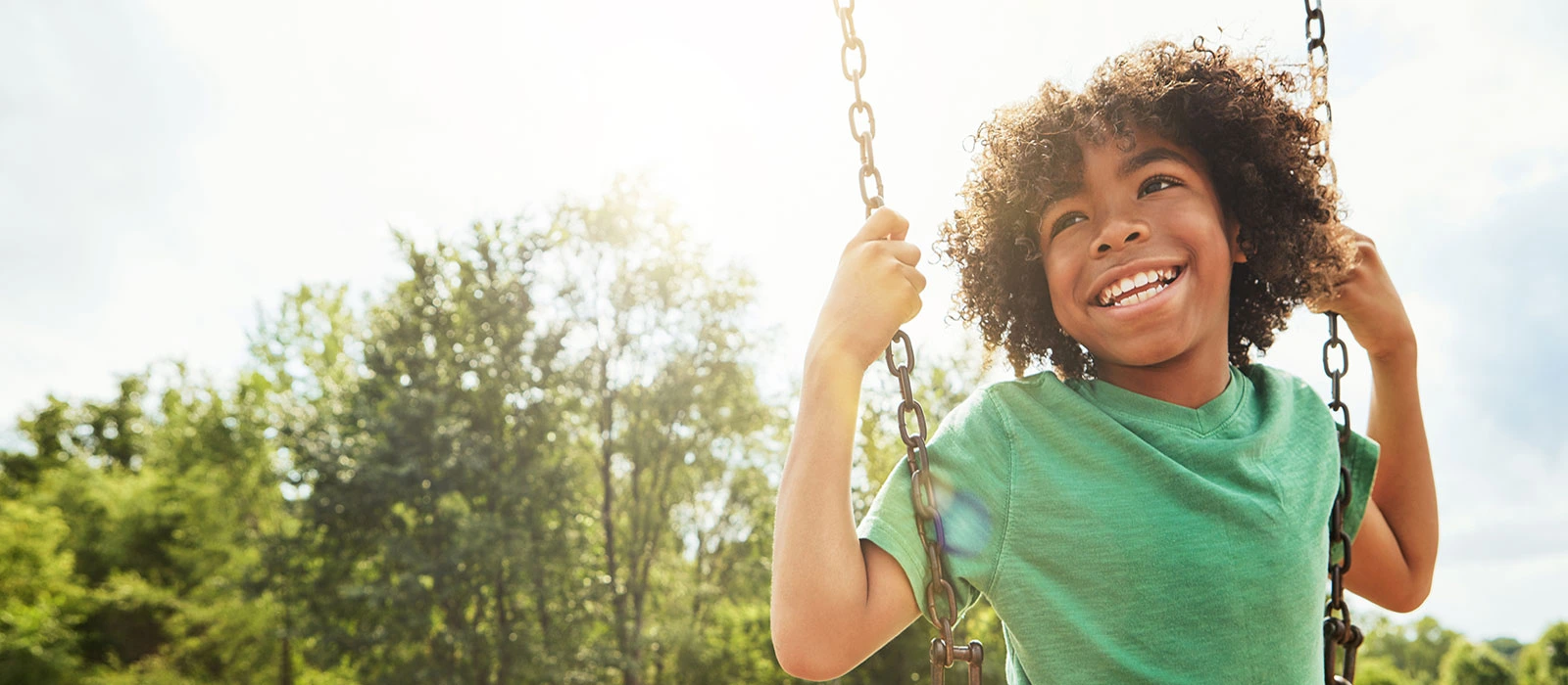 Boy laughing while swinging outdoors
