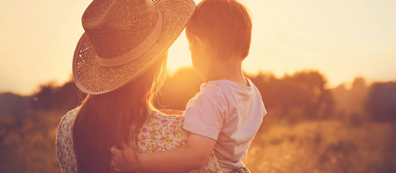 Silhouette of a parent holding a child at sunset