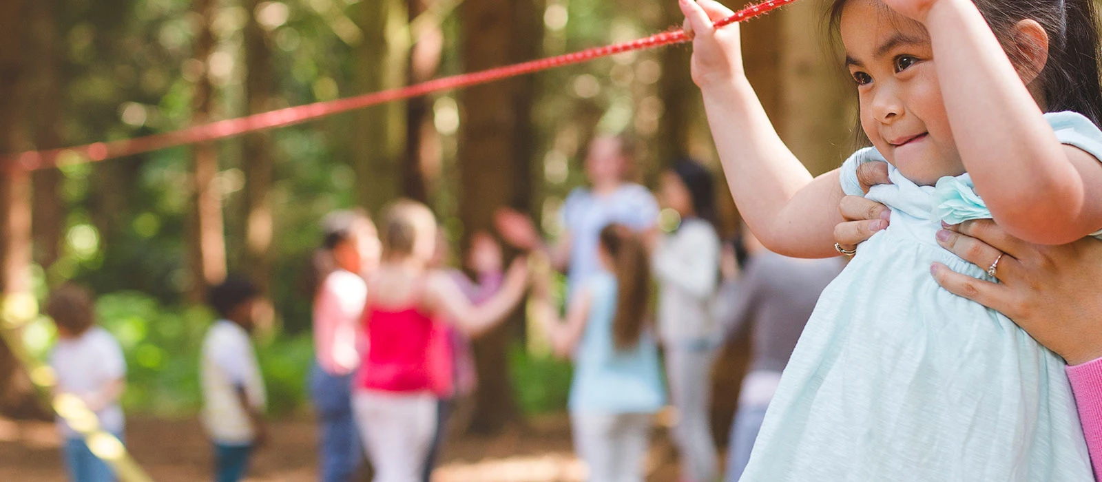 Child playing on a rope swing during an outdoor group activity